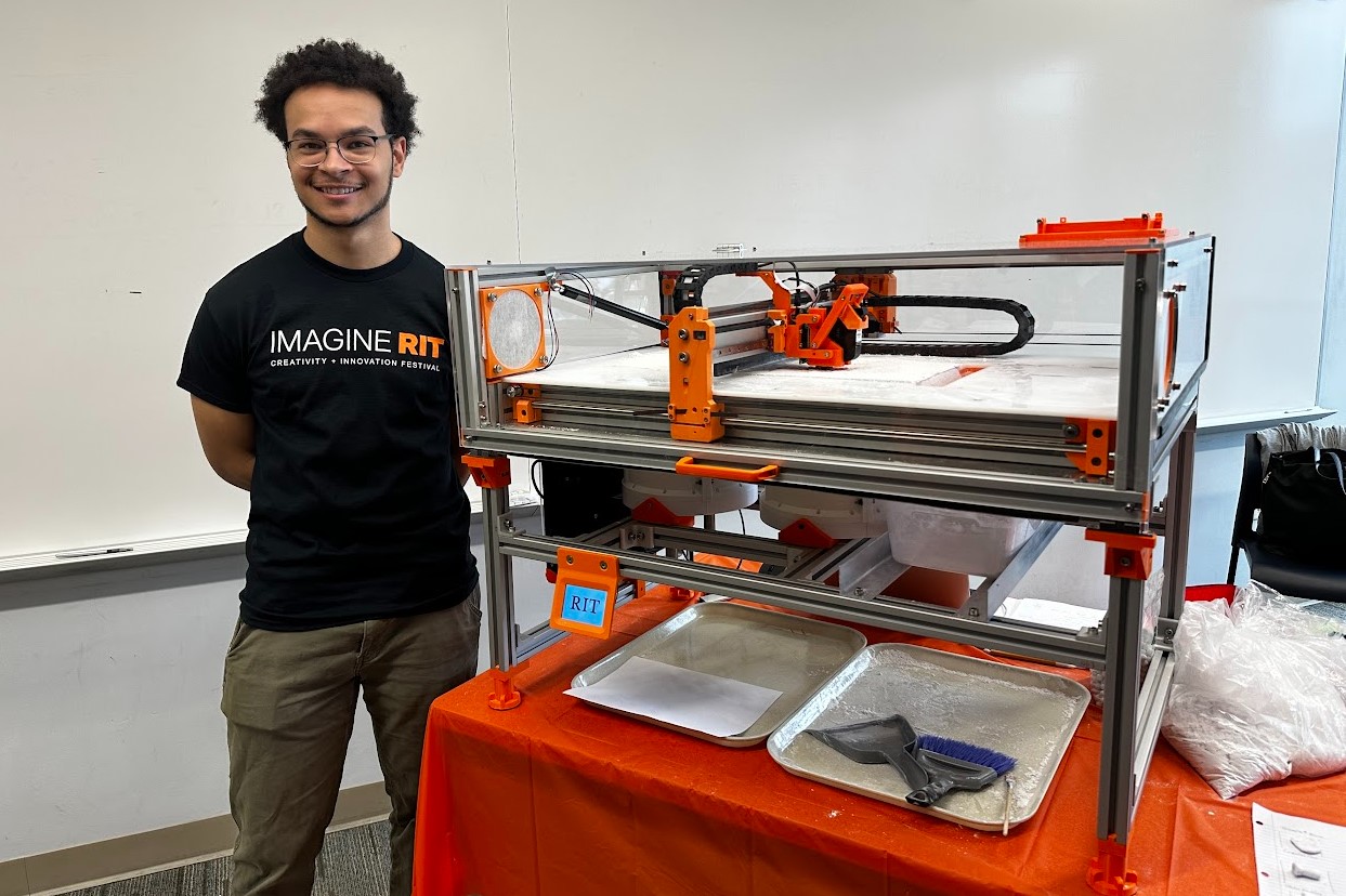 Michael Vasquez standing next to the completed binder-jet bone printer